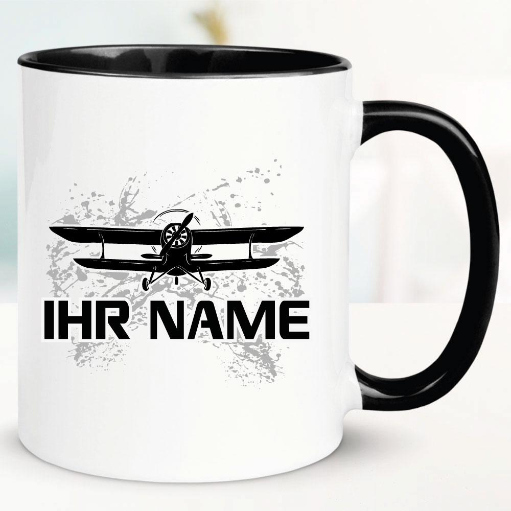 Schwarze Tasse mit Doppeldecker und Name bedruckt.